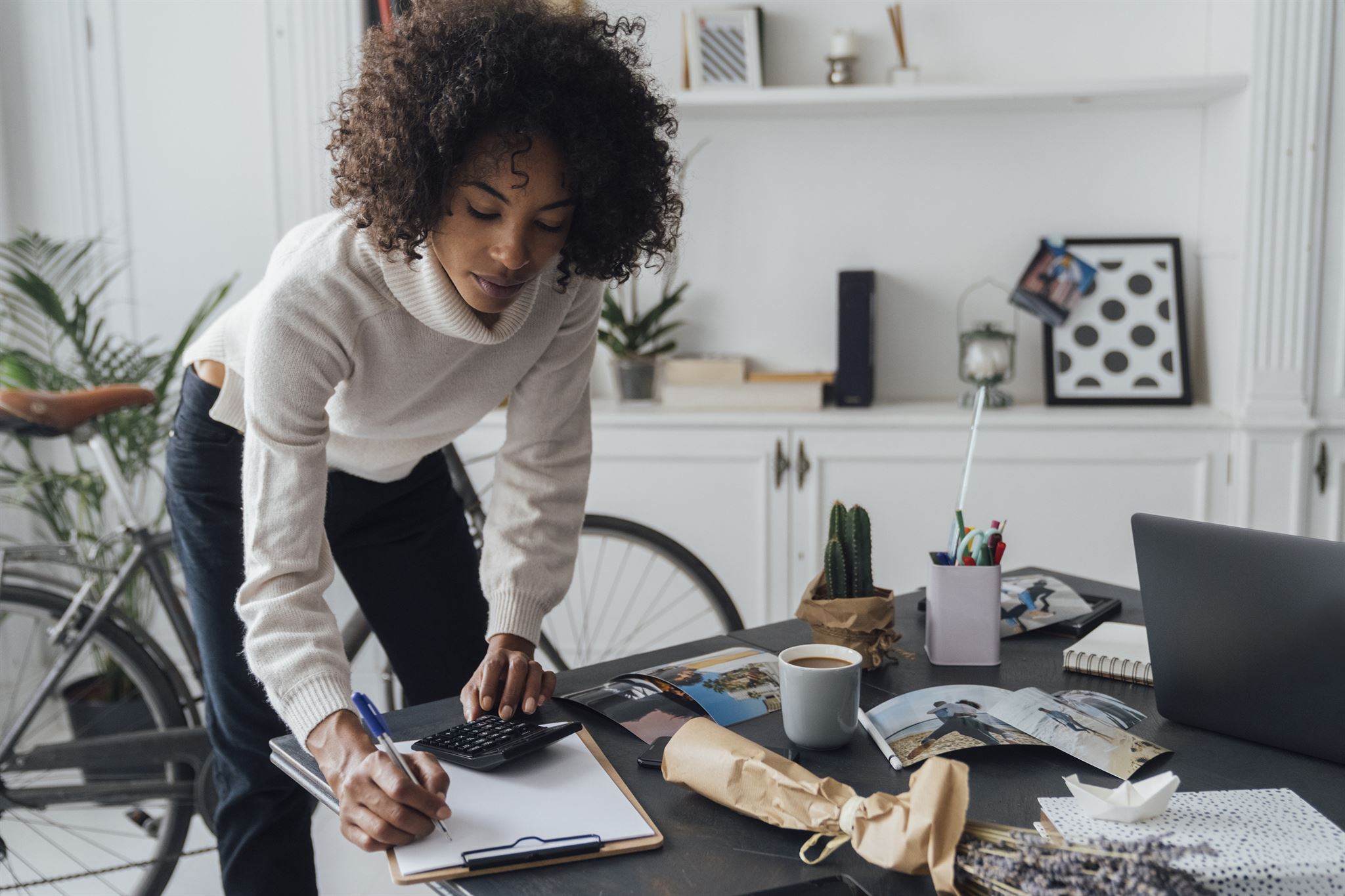 Woman-using-calculator-and-writing-in-home-office